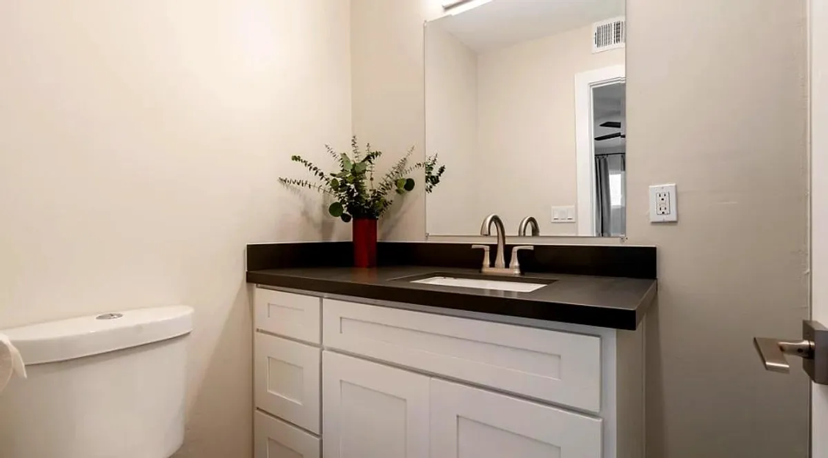 A stylish bathroom with a modern sink, large mirror, and a fresh flower arrangement. The clean lines and calming atmosphere highlight boutique amenities and a setting perfect for daily routines and relaxation.